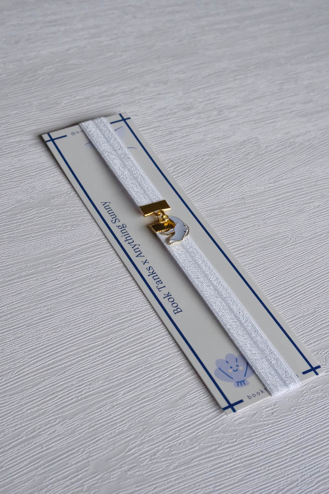 White leather strap with gold buckle on a gray textured background