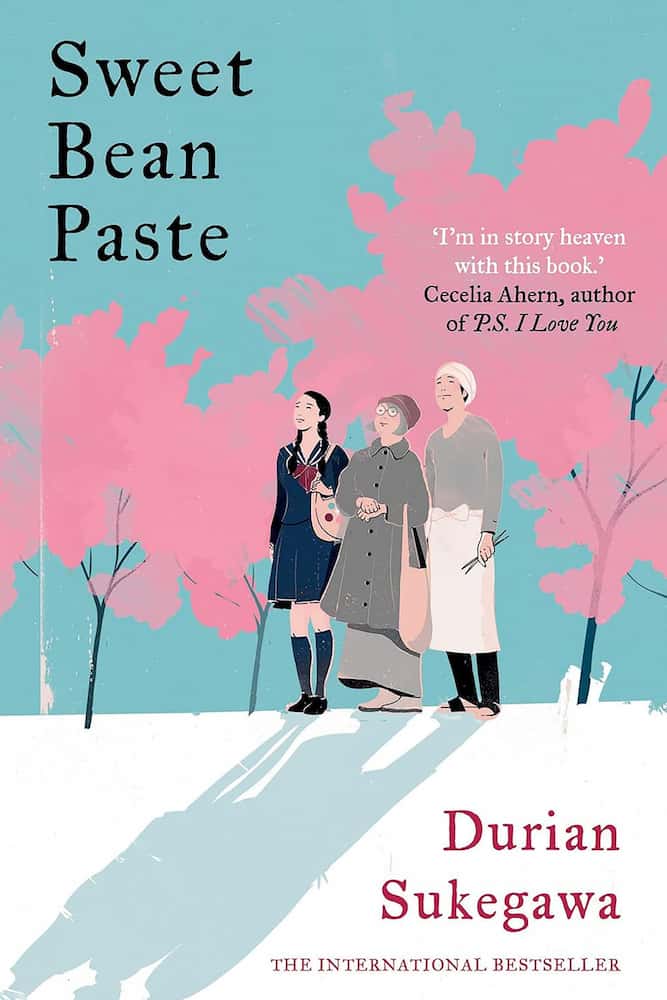 Book cover of 'Sweet Bean Paste' with three women walking under pink trees on a blue background.
